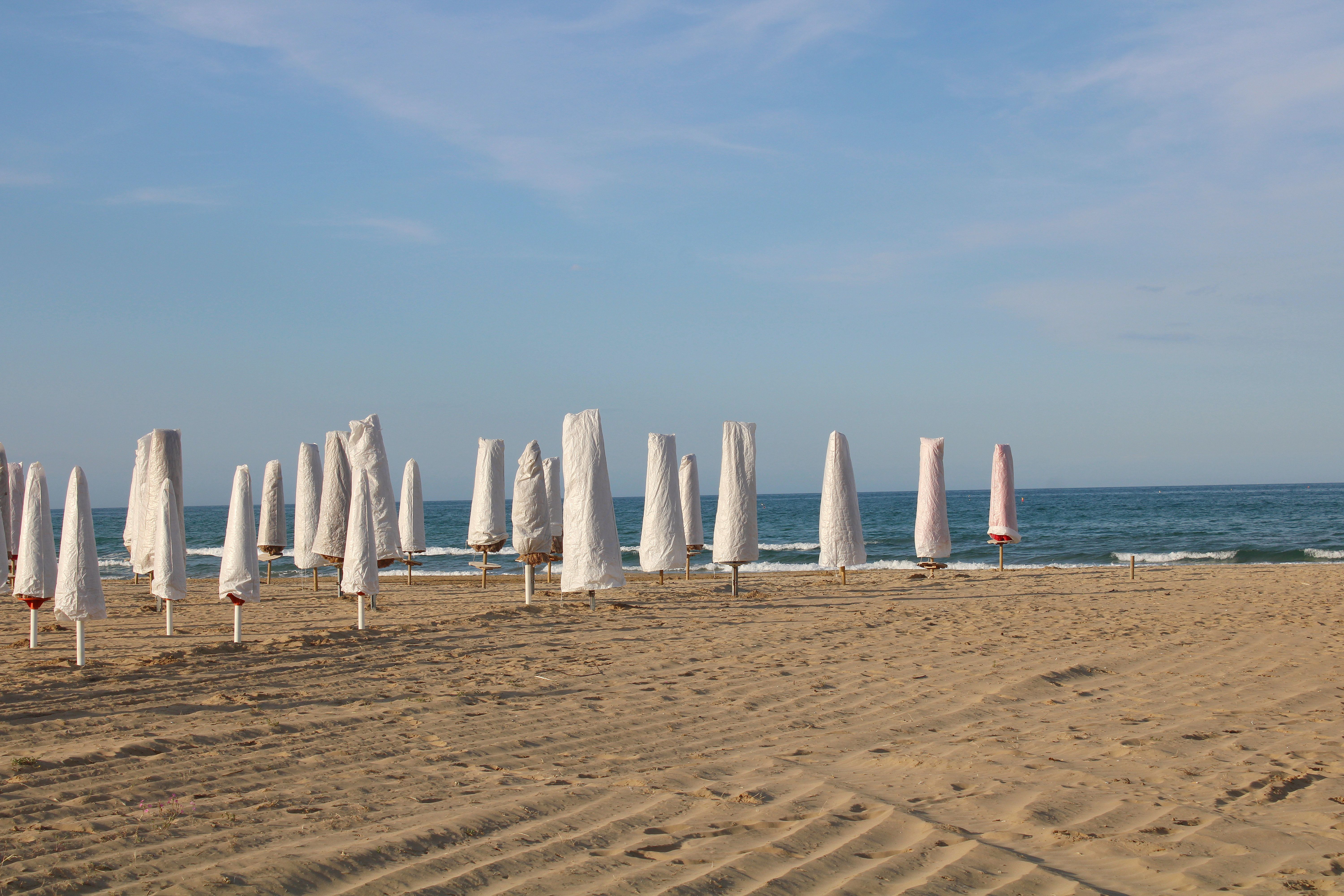 A serene beach scene with closed umbrellas and gentle waves in Abruzzo, Italy.