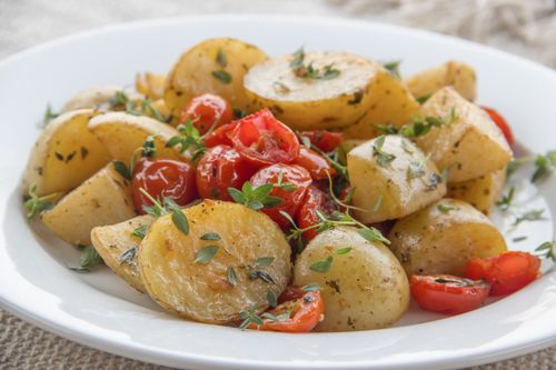 Free Savor the taste of herb-infused roasted potatoes paired with juicy cherry tomatoes for a delightful meal. Stock Photo