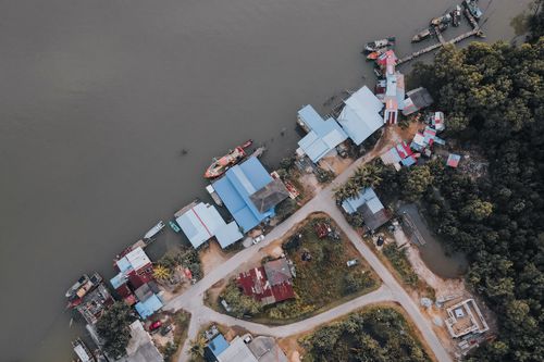 Free Aerial view of waterfront area in Chukai, Terengganu, Malaysia, showcasing houses, a river, and surrounding nature. Stock Photo
