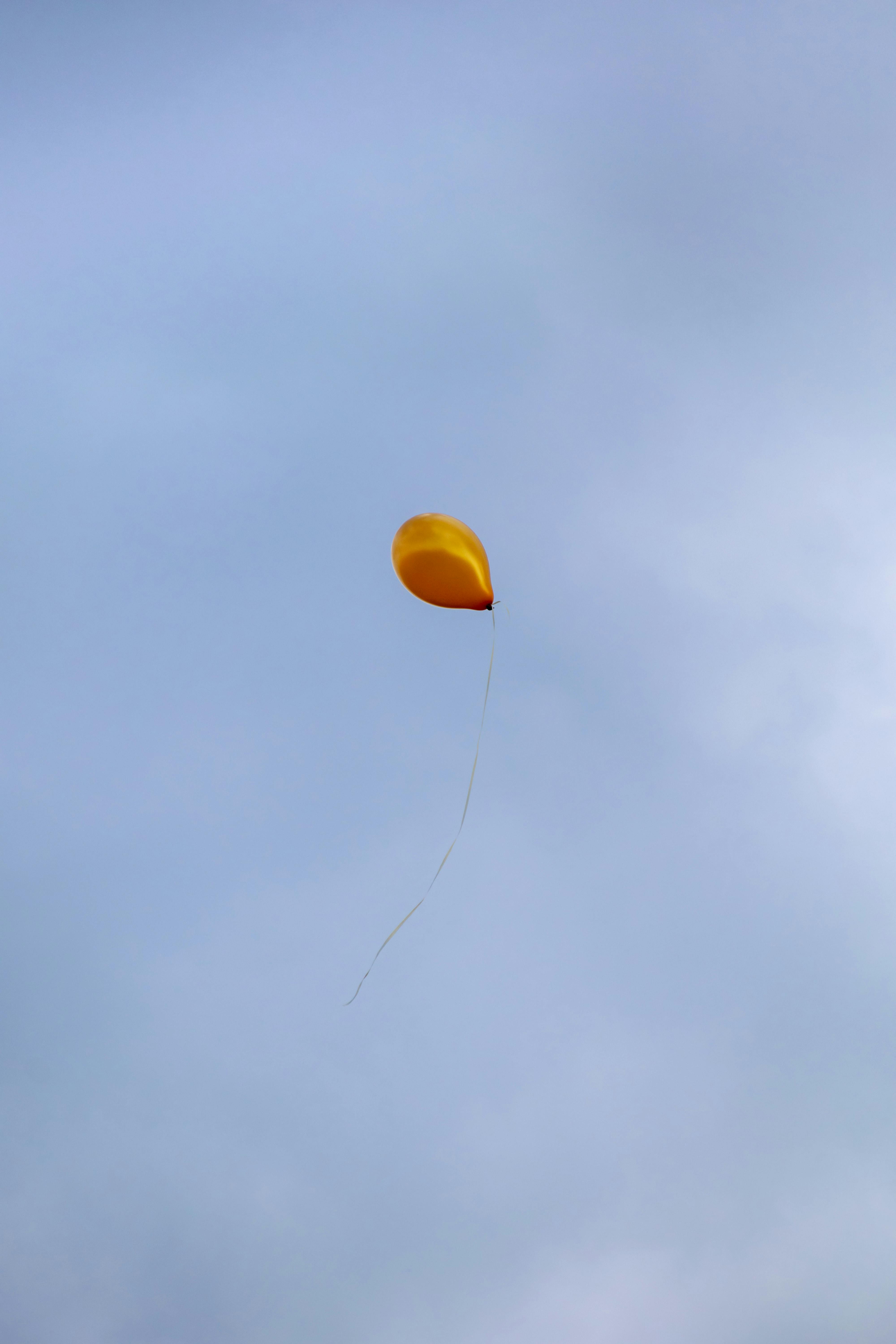 Yellow Balloon Soaring Under Gray Sky · Free Stock Photo