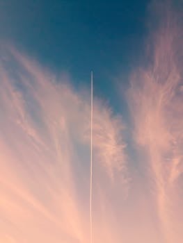 A scenic view of a dramatic sky with a single contrail, captured at sunset creating a serene atmosphere.