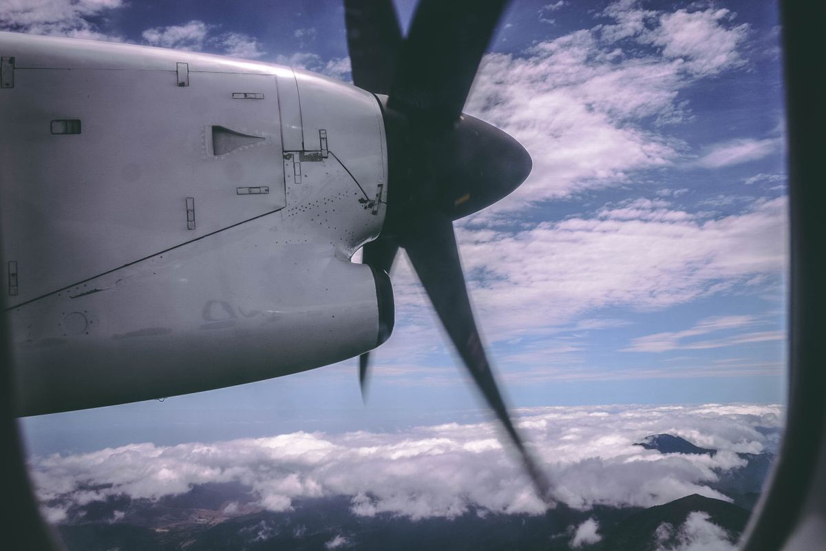 Beyaz propeller uçak bulutların üzerinde süzülürken güneş ışığı yansıyor