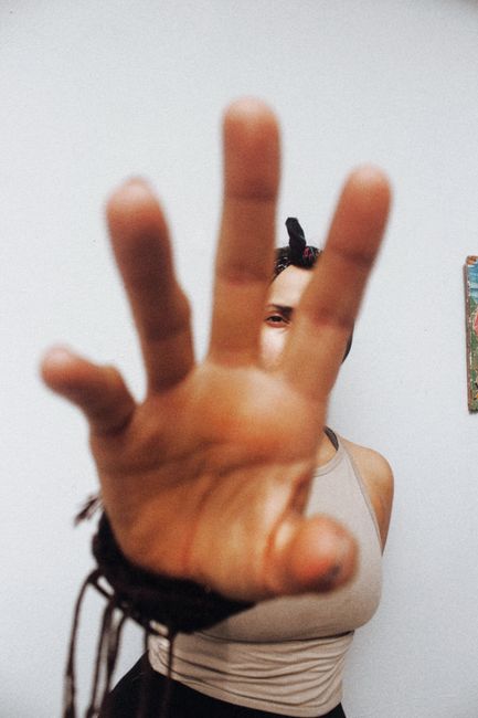 A creative portrait emphasizing an outstretched hand reaching towards the camera.