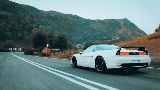 A sleek white sports car speeding through a scenic mountain road during the day.