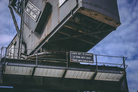 An industrial crane captured with detailed infrastructure against a cloudy sky backdrop.