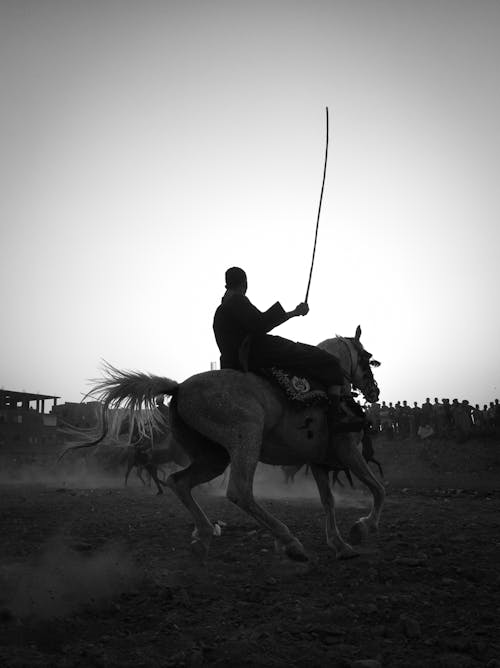 Black and White Picture of Man Riding a Horse