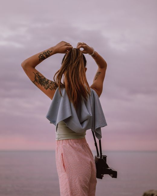 Tattooed woman in contemplation by the sea, embracing nature's beauty.