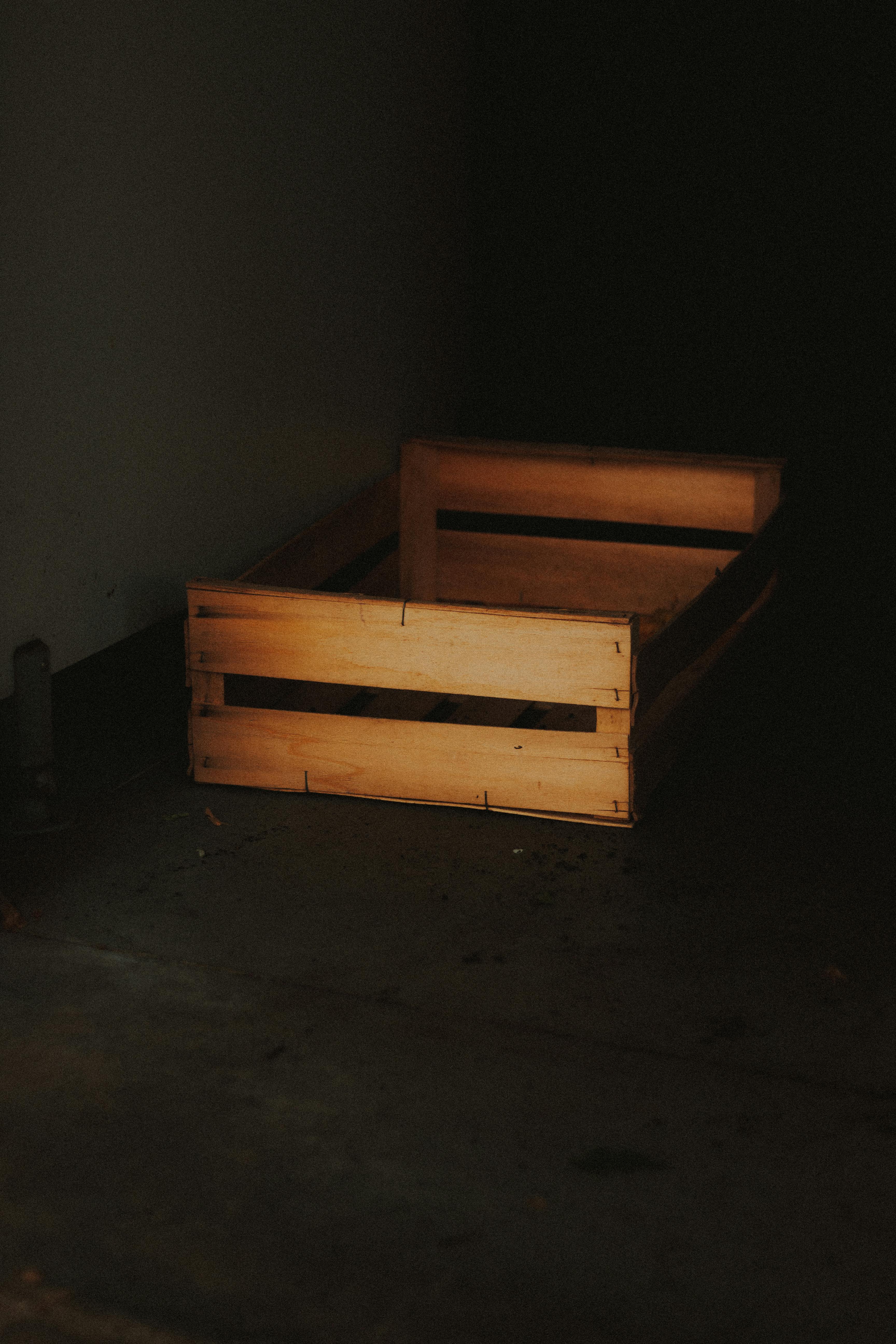 Free Atmospheric shot of a rustic wooden crate in a dimly lit warehouse corner. Stock Photo