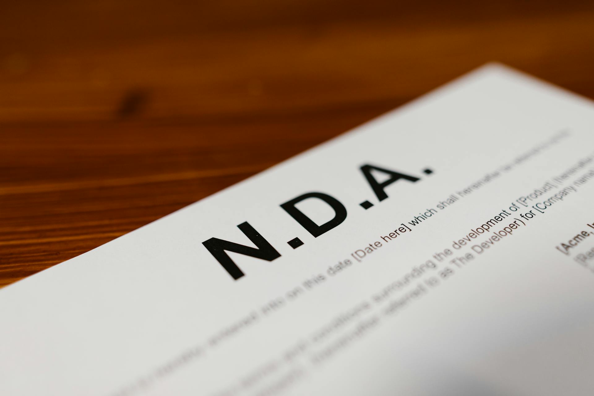 Focused close-up of an NDA document on a wooden desk, highlighting contract details.