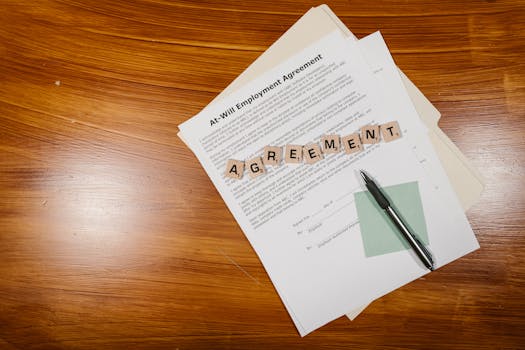 A flat lay of an employment agreement with Scrabble tiles on a wooden table.