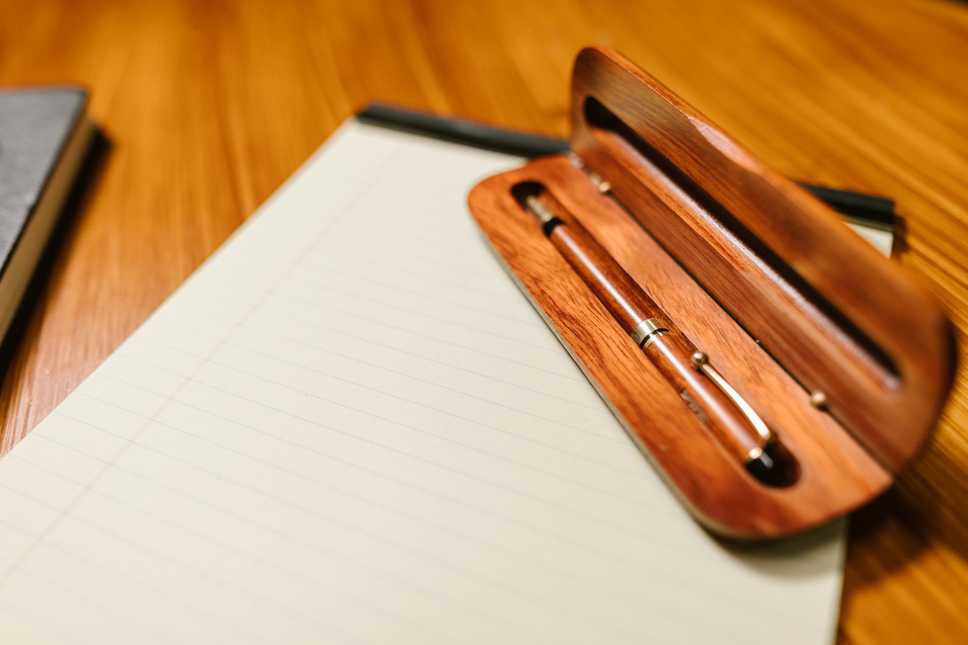 An elegant wooden pen rests on a lined notepad, perfect for writing and note-taking.
