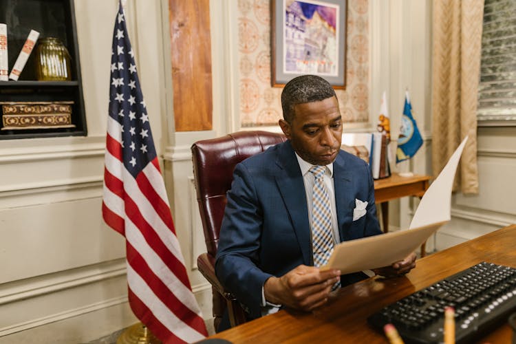 A Man In Suit While Reading A Document