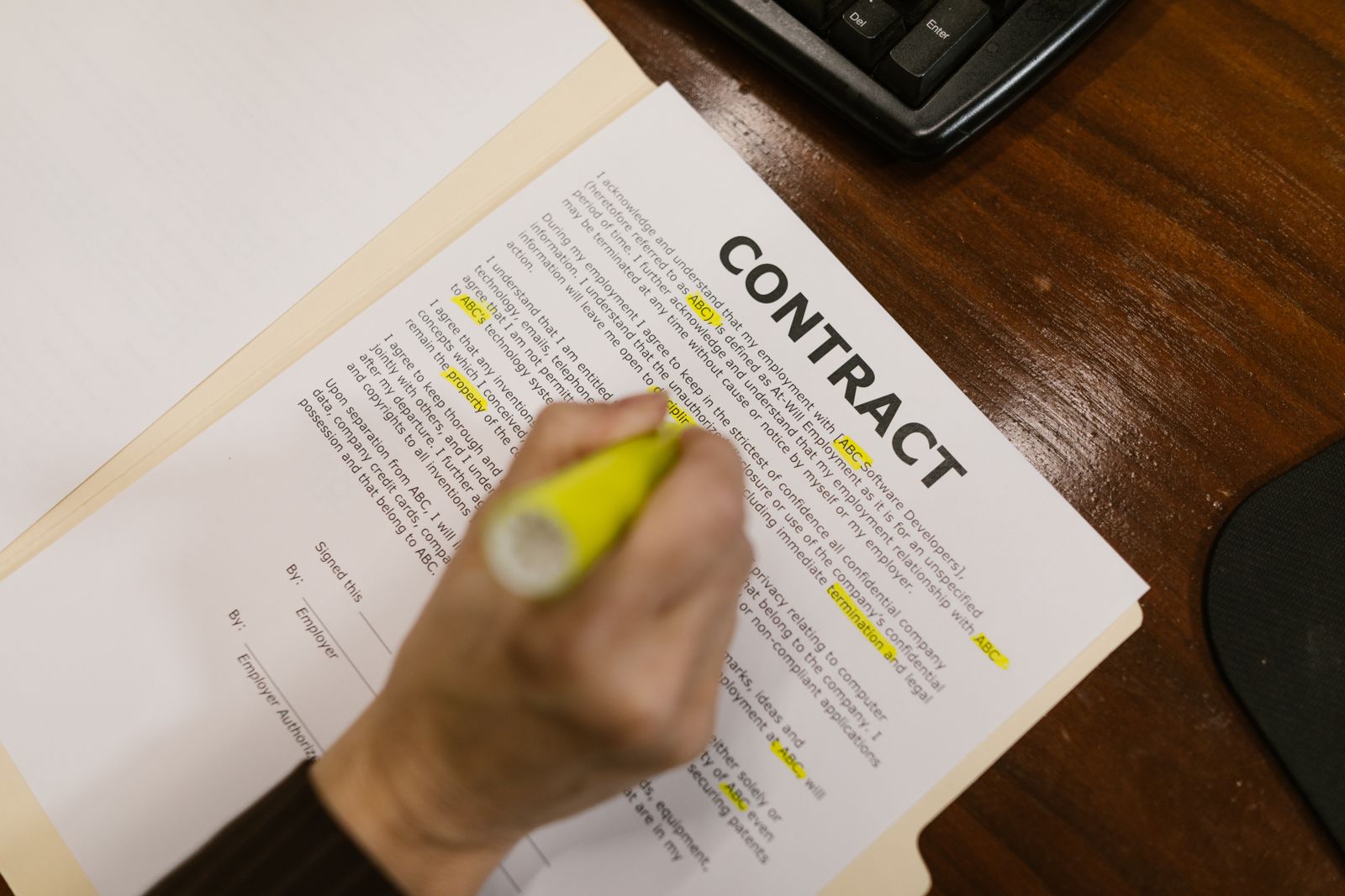 Yellow highlighter marking specific phrases in a printed contract document