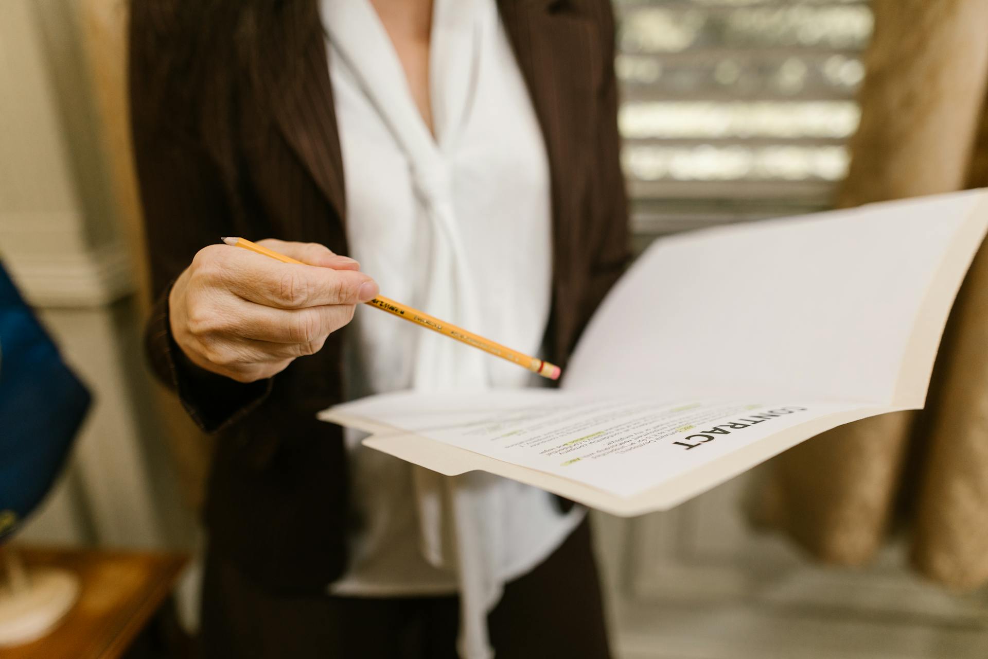 A businesswoman holds a contract, pointing with a pencil. Legal and corporate setting.