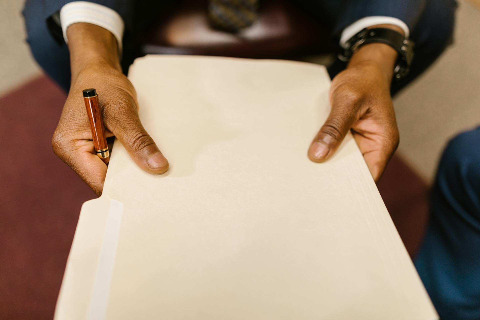 A business professional with a suit holding a legal folder and pen, indicating formal paperwork handling.