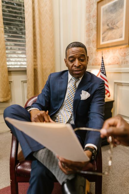 Photo by RDNE Stock project A businessman in a suit reviews documents in an office with an American flag.