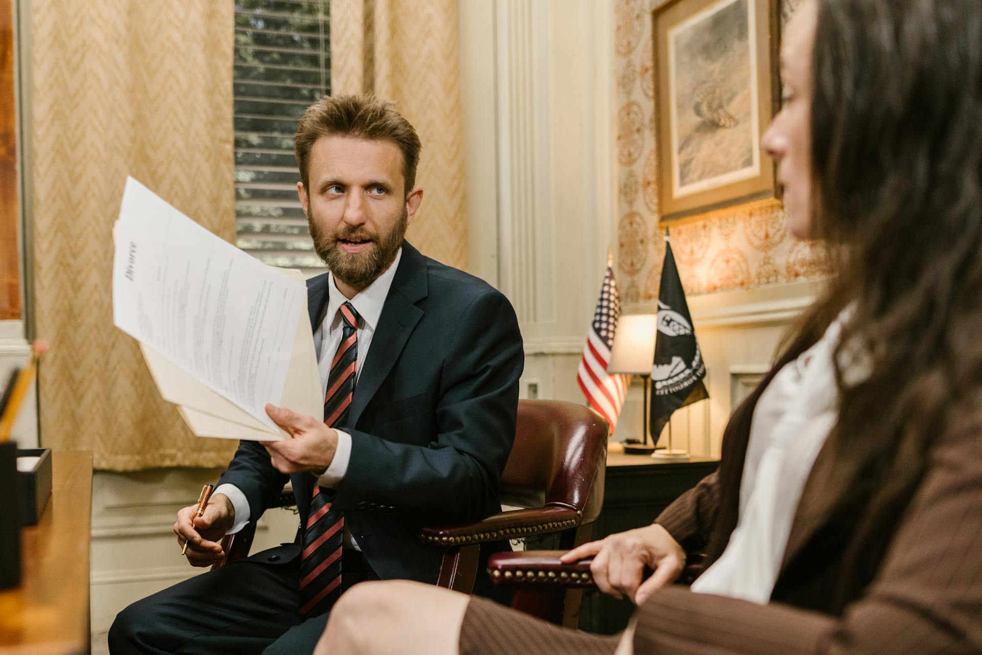 Lawyer in suit discussing documents with client in an office setting.