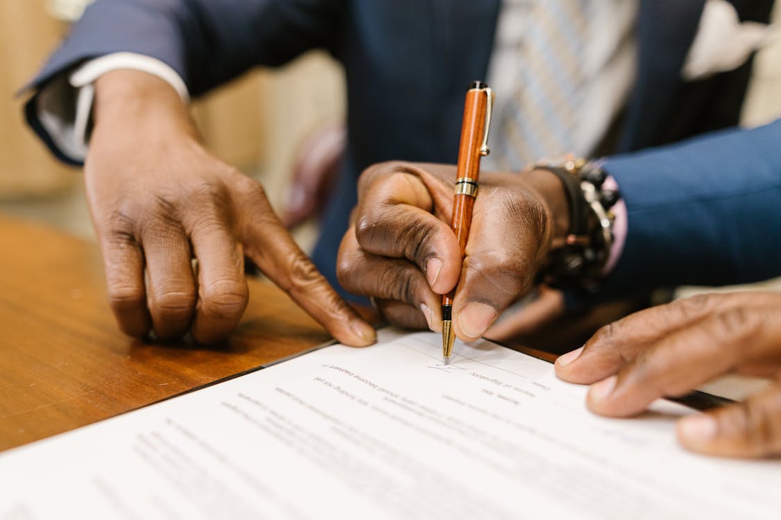 Close-Up Shot Of A Person Writing On A Contract