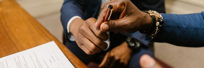 Two businessmen in suits finalize a contract, highlighting teamwork and agreement.