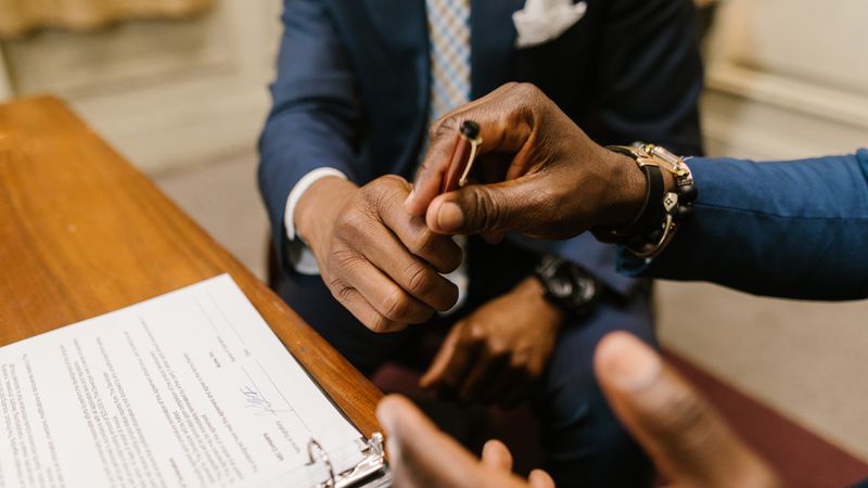 Two businessmen in suits finalize a contract, highlighting teamwork and agreement.