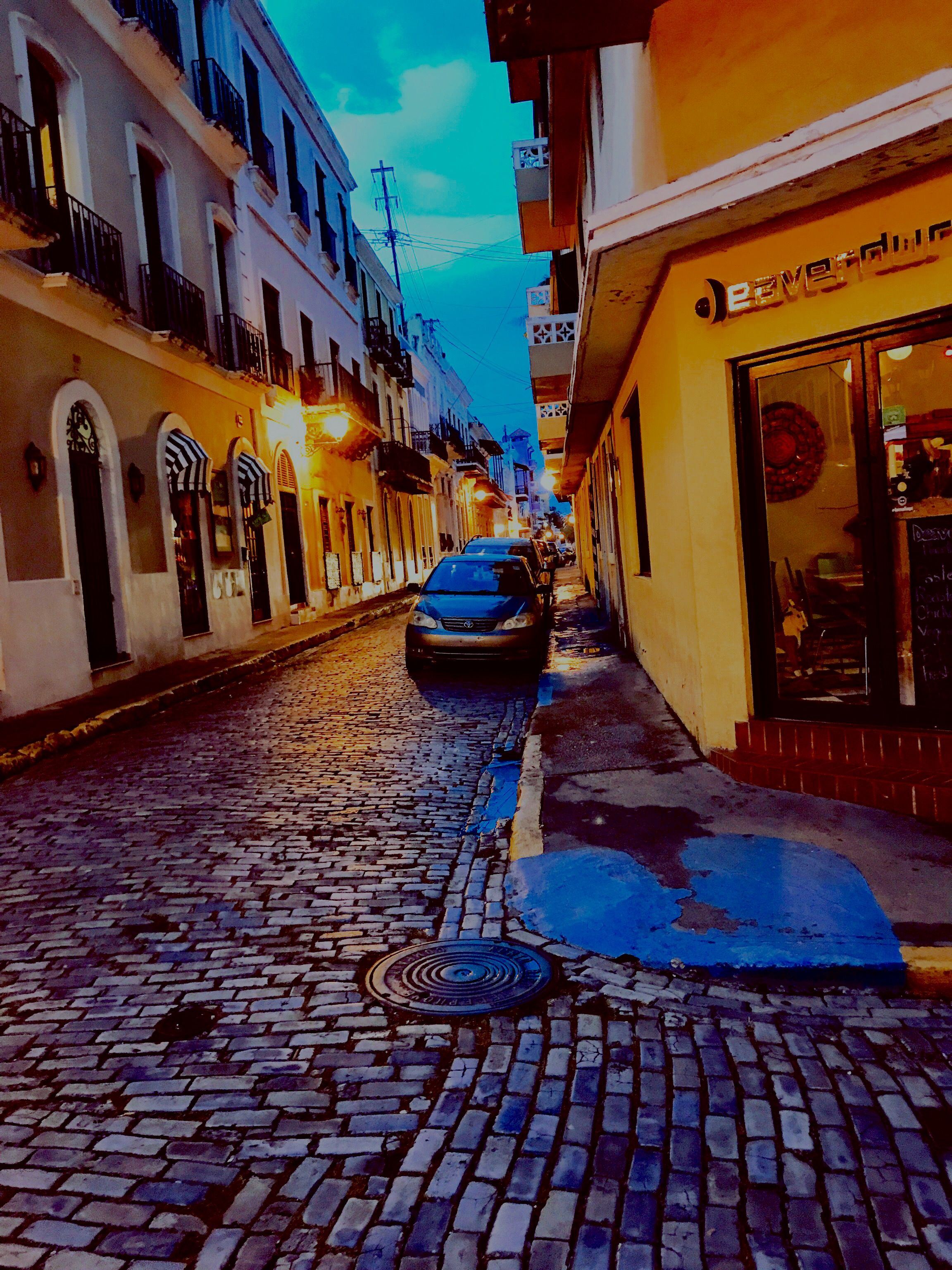 A historic cobblestone street corner in San Juan, Puerto Rico, illuminated at dusk