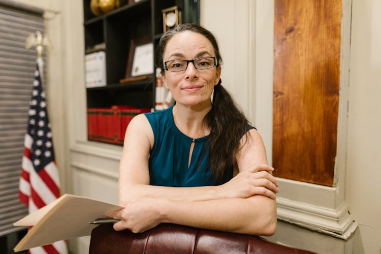 Woman In Blue Top Holding A Folder And Pen