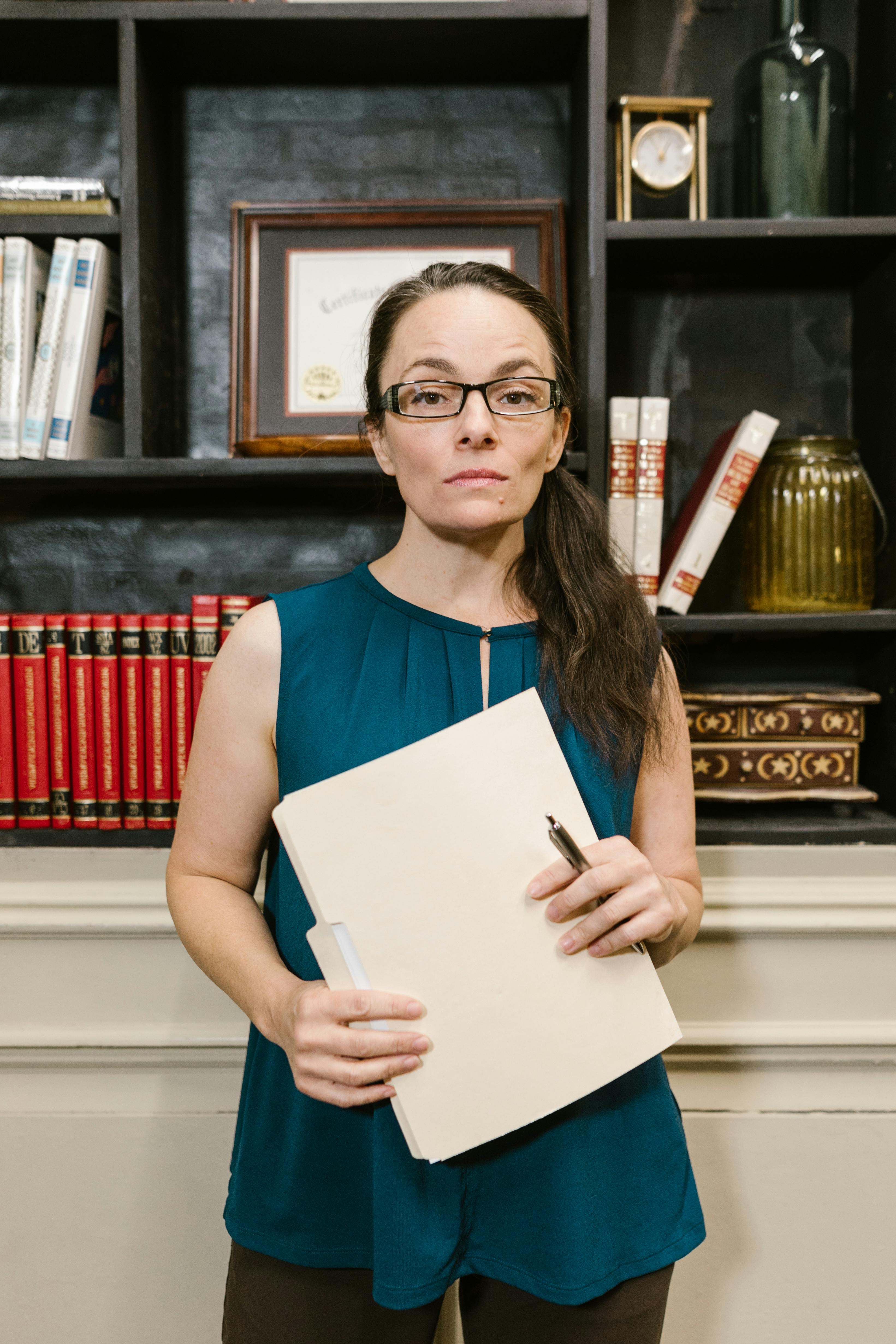 a woman in eyeglasses holding a folder