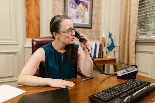 A businesswoman engaged in a phone conversation at her desk in an office.