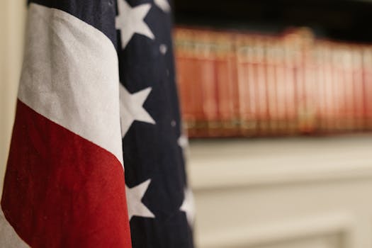 Detailed close-up of an American flag indoors with blurred bookshelf in the background.