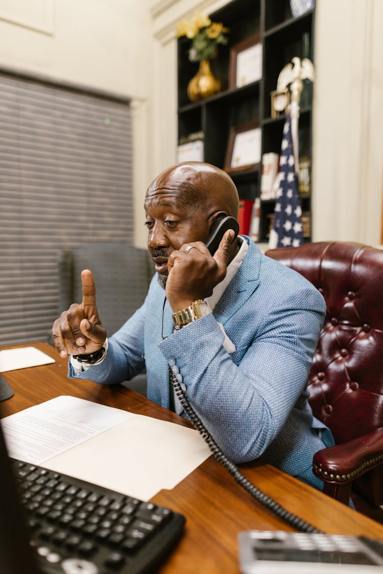 A Man Talking On The Phone At His Work Desk
