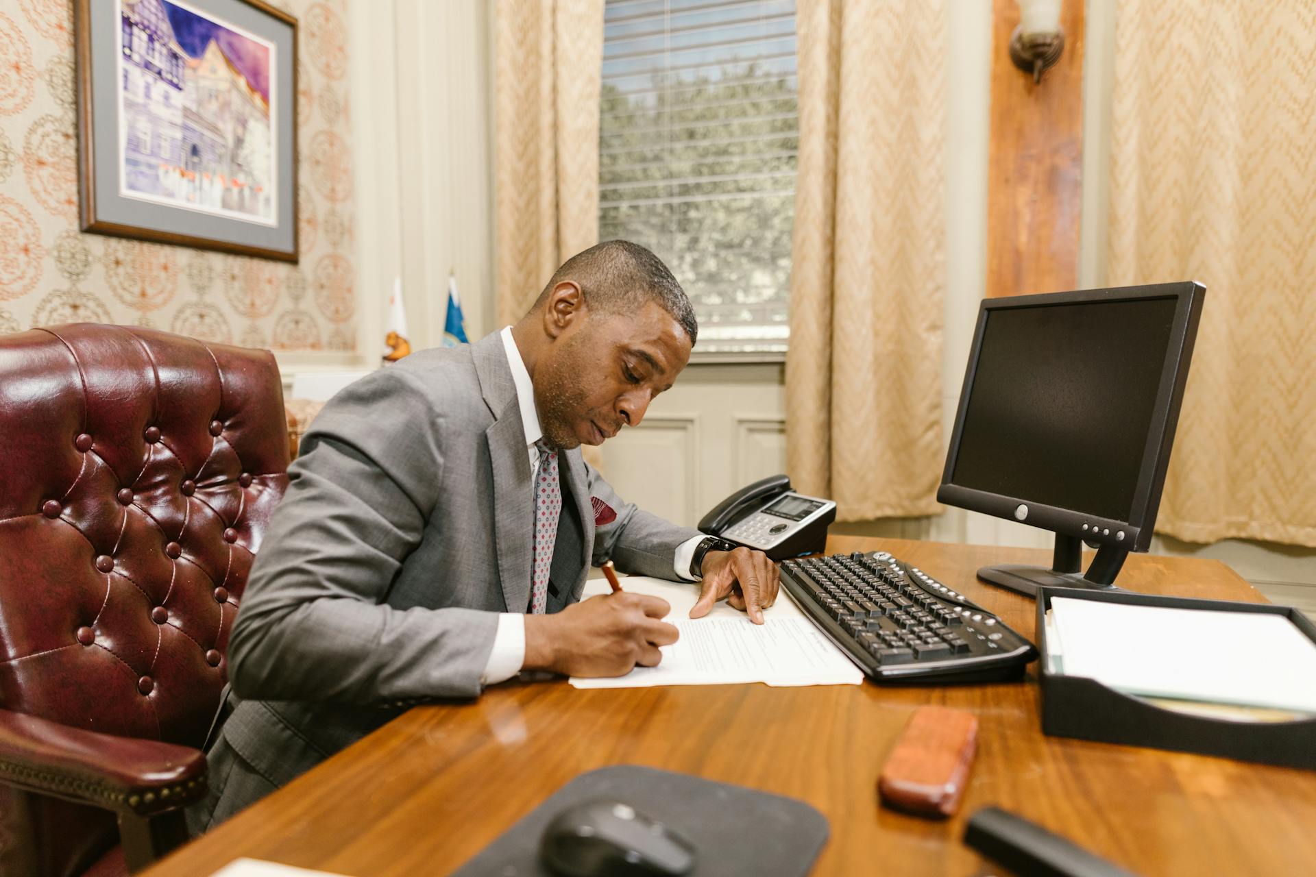 Lawyer writing at desk in a law office, focusing on documents.