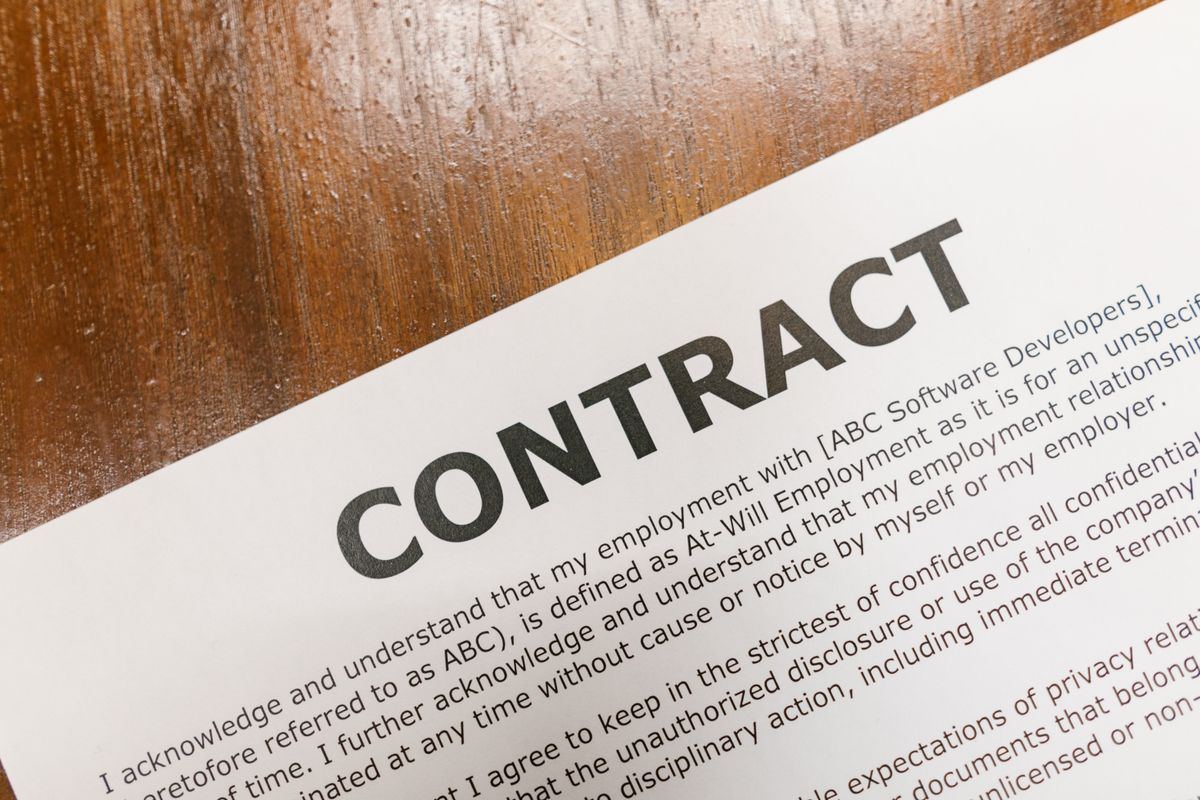 A detailed close-up of a printed contract document on a wooden table surface.