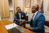 2 Men in Blue Suit Jacket Sitting Beside Brown Wooden Table