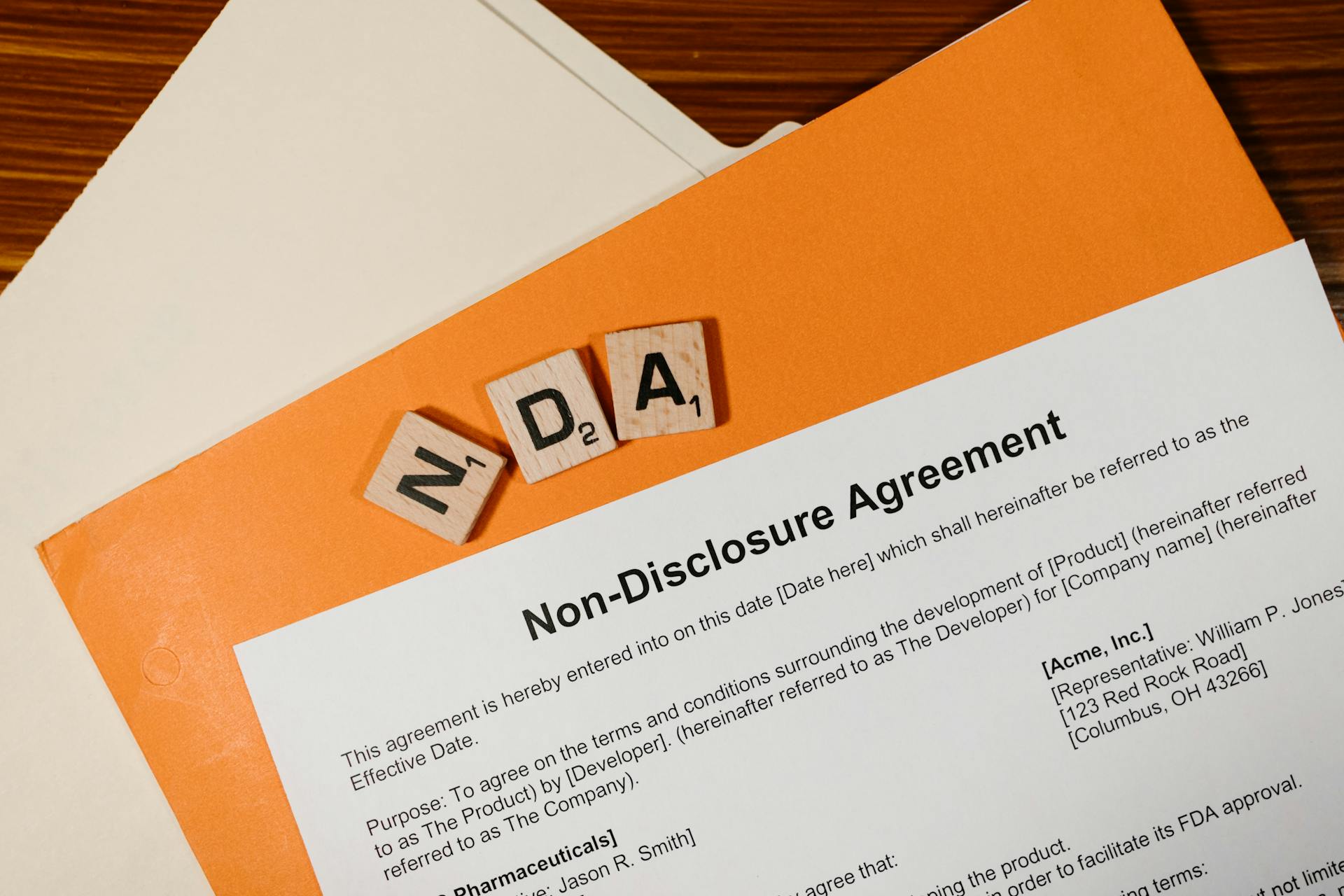 Top view of a Non-Disclosure Agreement with NDA in Scrabble tiles, emphasizing confidentiality.