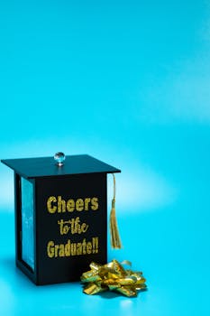 A decorative graduation gift box styled as a cap with tassel against a bright blue background.