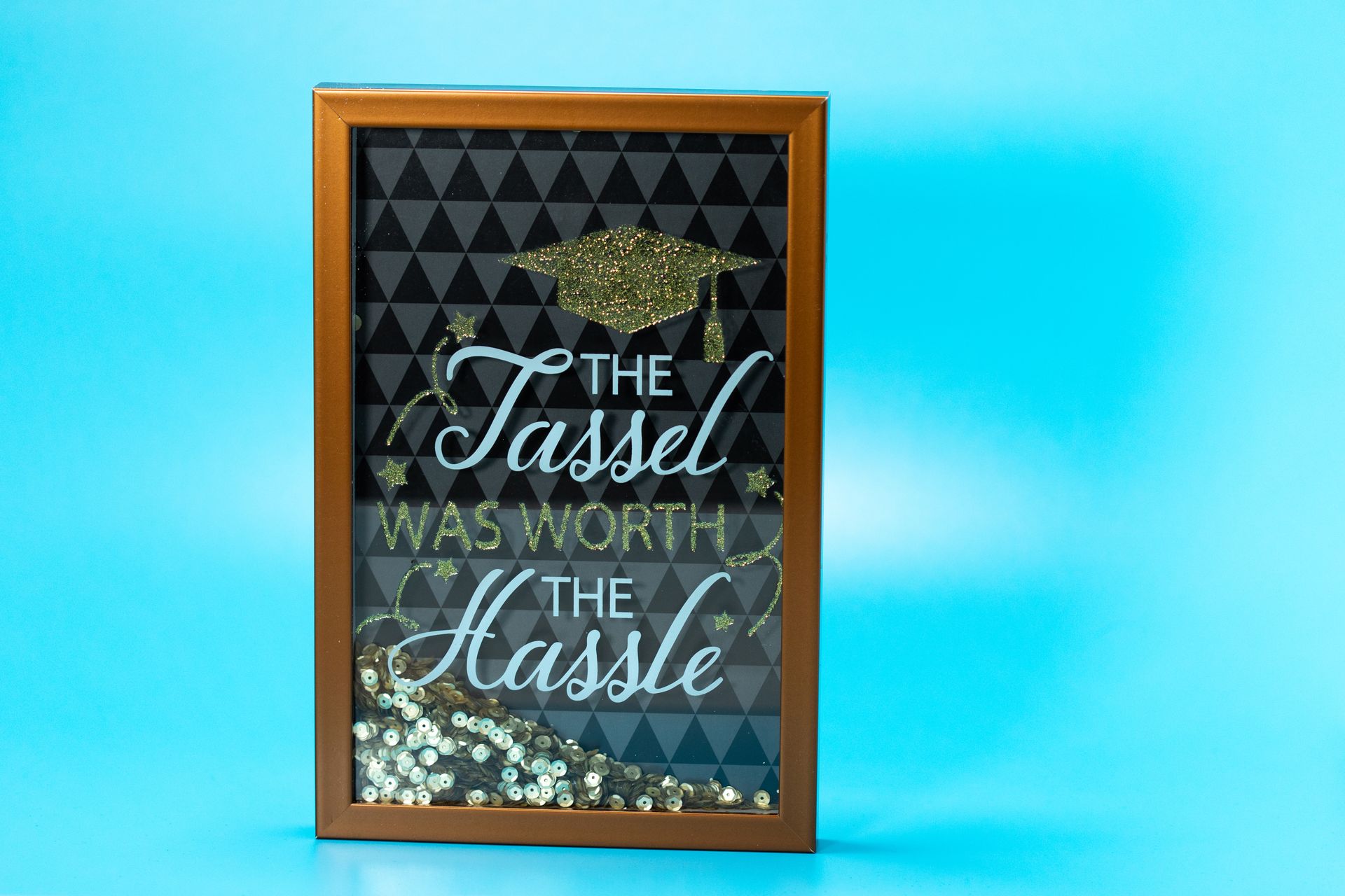 Framed quote 'The Tassel Was Worth The Hassle' on light blue background.