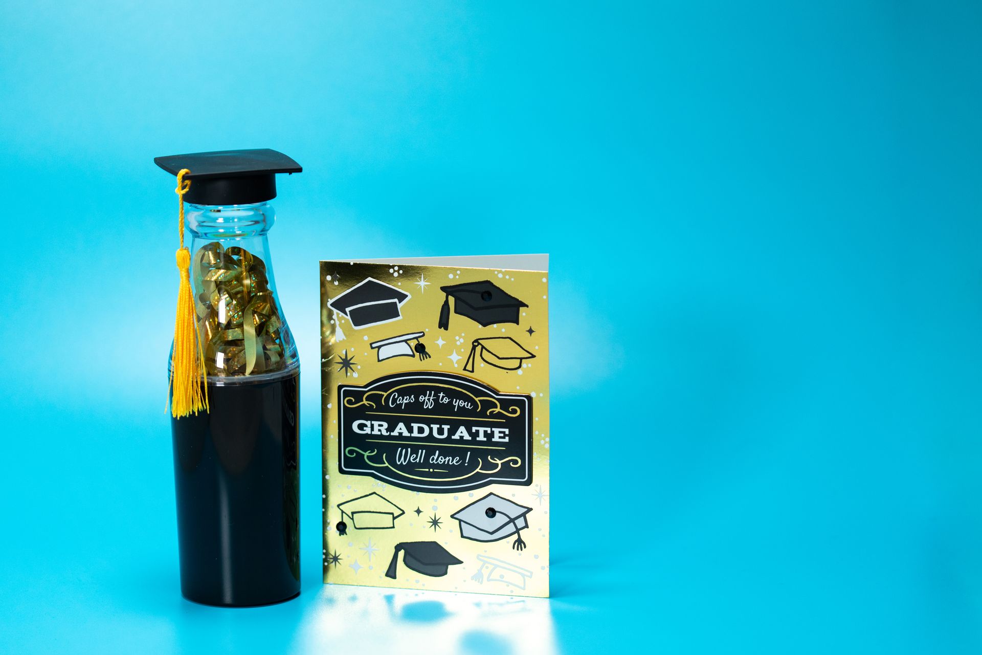 A graduation-themed setup with a bottle and card on a blue background.