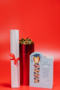 Graduation set featuring a diploma, gift box, and card on a red background.