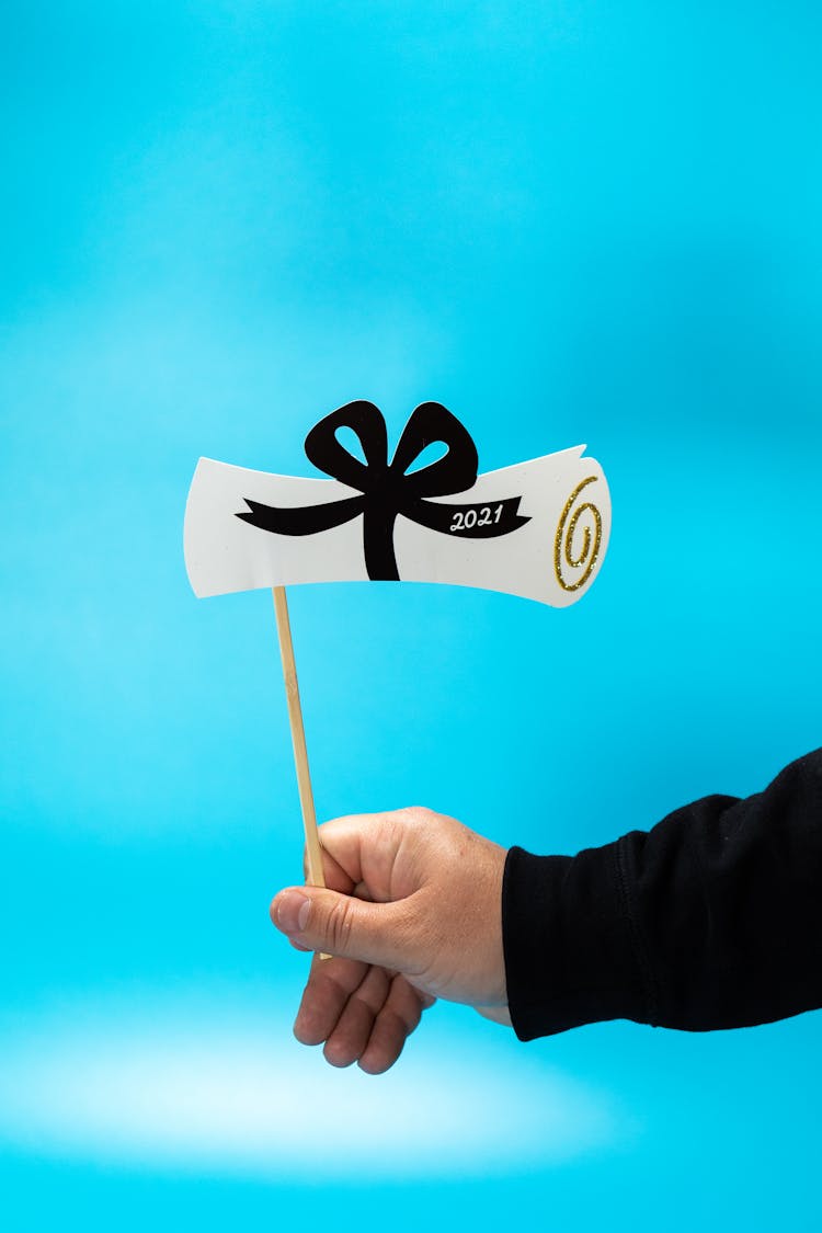 A Person Holding A Graduation Themed Cake Topper