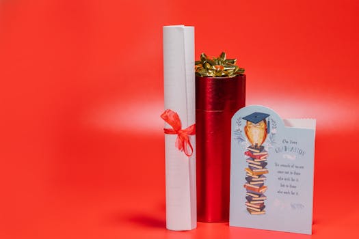 A rolled diploma, red gift container, and graduation card on a vibrant red background.