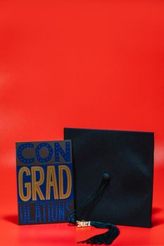 Graduation cap and card displaying 'CONGRADULATIONS' on vibrant red background.
