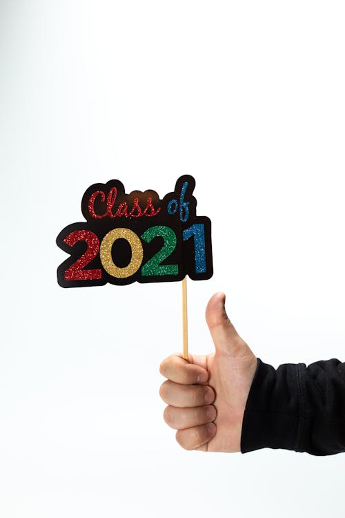 Close-up of a Person Showing Thumbs Up and Holding a "Class of 2021" Sign 