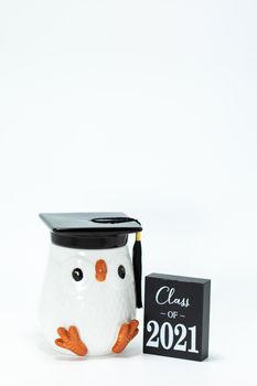 Penguin figurine wearing a graduation cap next to a 2021 sign, symbolizing accomplishment.