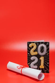 Vertical shot of a rolled diploma with a 2021 graduation card on a vibrant red background.