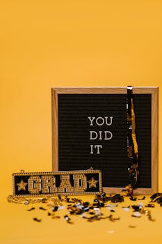 Graduation celebration with board sign saying 'You Did It' on vibrant yellow background.