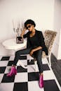 一位时尚的女人穿着充满活力的靴子，戴着太阳镜，在别致的工作室里摆姿势，地板是方格图案的