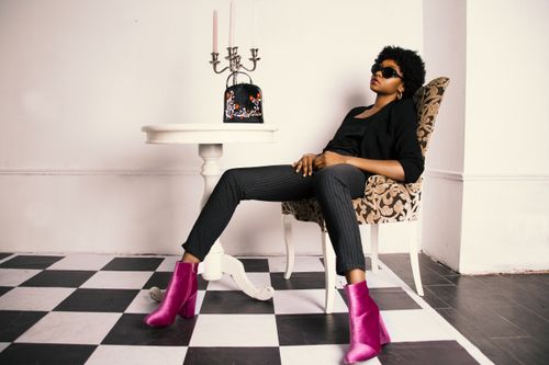 Free Fashionable African American woman posing stylishly indoors with modern decor. Stock Photo