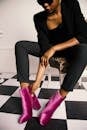 在别致的室内环境中，优雅的女人调整着粉红色的靴子，展现出时尚的现代风格
