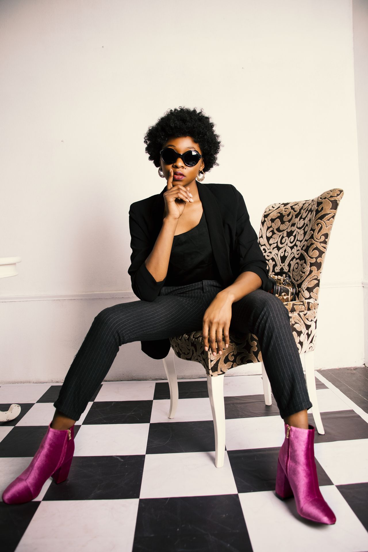 Woman in a black blazer and pinstripe trousers with fuchsia boots