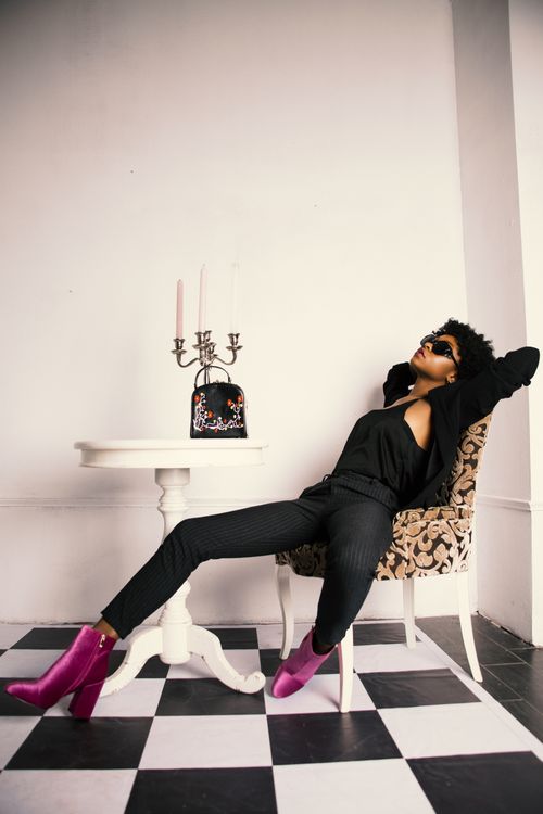 Free A fashionable woman lounges indoors with trendy decor and vibrant shoes. Stock Photo